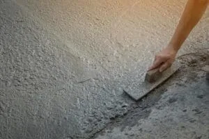 Contractor using a float to smooth a concrete surface