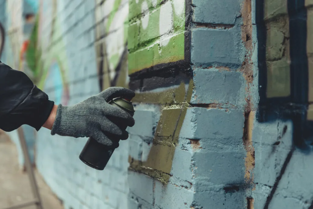 Graffiti removal from a brick wall using a pressure washer on a commercial property.