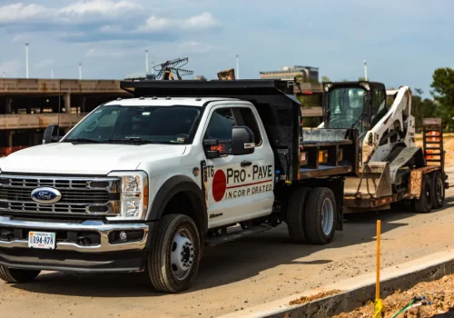 Pro-Pave work truck transporting skid steer for commercial asphalt paving and pavement maintenance