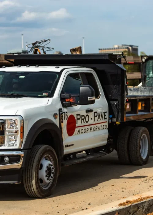 Pro-Pave work truck transporting skid steer for commercial asphalt paving and pavement maintenance